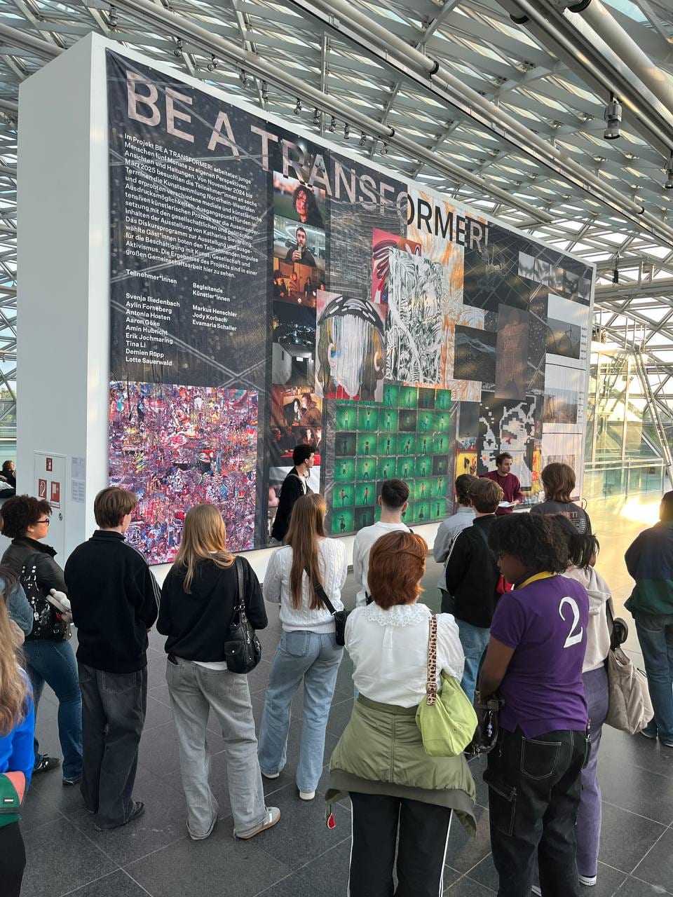 A group of visitors standing in front of the banner at K21, 1/4 at the lower left.