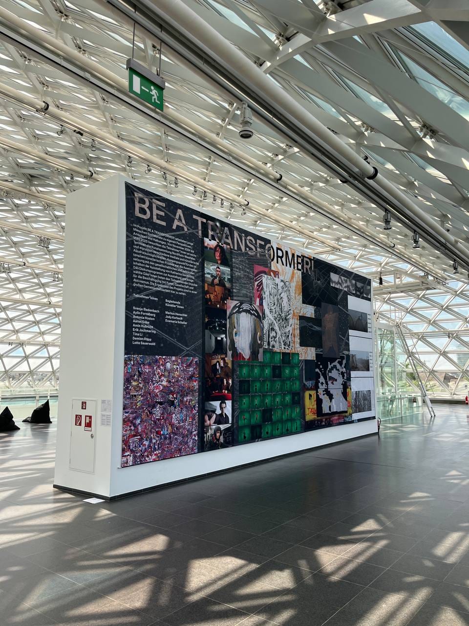 The banner seen from the side, the 1/4 collage in the lower left corner, sunlight falling through the glass roof.