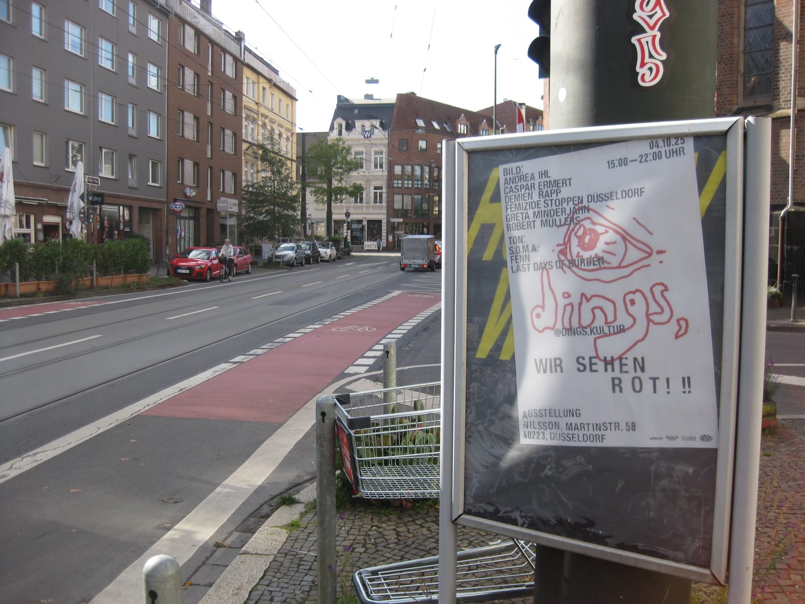 Poster for dings. WIR SEHEN ROT!! in a display case on a street.