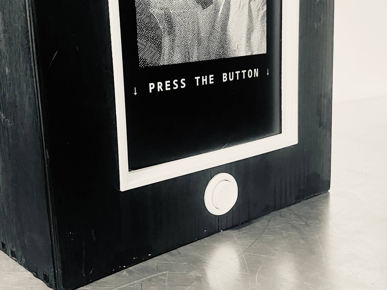 Close-up of the crate front: the screen reads PRESS THE BUTTON with arrows pointing down to the round white button.
