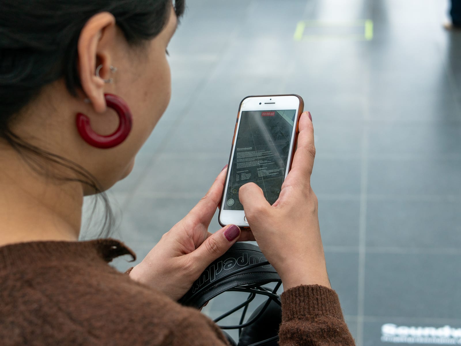A visitor listens to a piece on her phone after scanning a QR code on the floor.